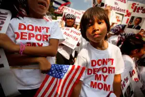 Children of immigrants holding signs, one reads "Don't Deport My Mom.